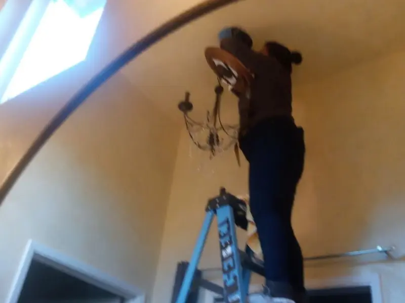 Electrician installing a chandelier in a Somers residence